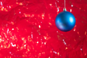  Blue ball as a Christmas decoration on a red background with bokeh effect for New Year's greetings