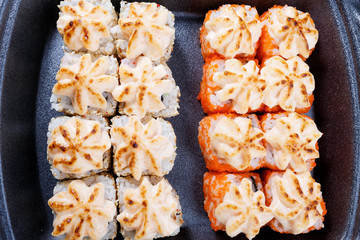 Sushi in plastic packaging. Baked sushi with flying fish roe. Sushi in a plastic box close up.