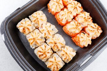 Sushi in plastic packaging. Baked sushi with flying fish roe. Sushi in a plastic box close up.