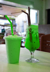 Delicious exotic alcoholic cocktail with fresh fruits and smoothies bright green color on a table in a tropical bar