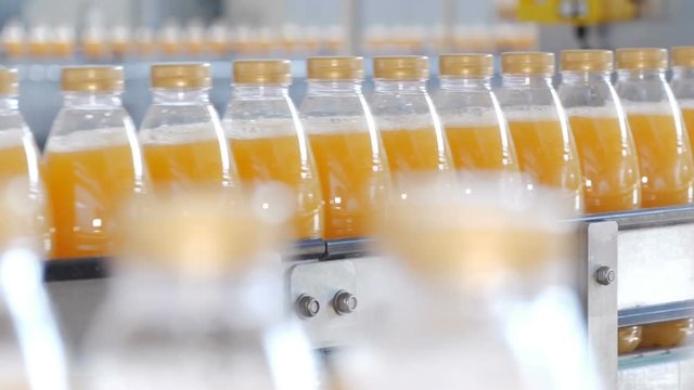 Bottles filled with juice are moving along the conveyor