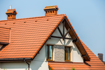 Top of big modern expensive residential house cottage with steep shingled brown roof, high brick...