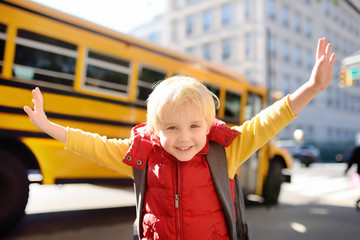 Pupil with schoolbag with yellow school bus on background