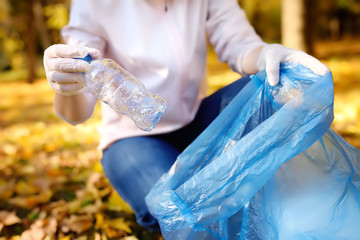 Volunteer picking up the garbage and putting it in biodegradable trash-bag on outdoors.