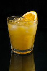Orange juice in the glass. Reflection. Dark background. Isolated.