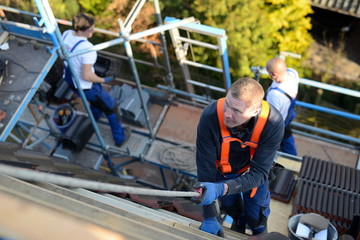 Dachdecker bei Instandhaltungsarbeiten: Sicherheitsgurt nach Vorschrift anlegen und nutzen,...