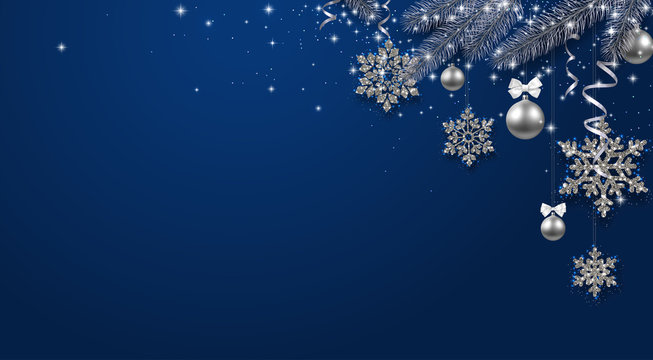 Blue shiny festive background with fir branch, silver balls and snowflakes.