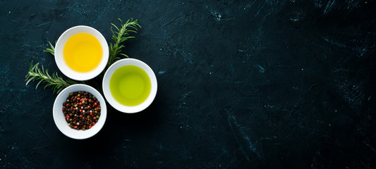 Olive oil, sunflower oil and rosemary. On a black stone background. Top view. Free copy space.