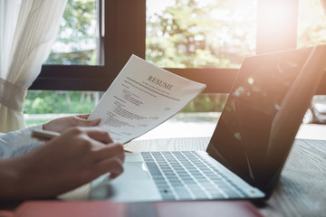 woman holding resume application with using computer laptop digital to job search on internet....