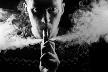 Portrait of a boy with a shadow on a serious face  with a colored backlight of monochrome smoking a...