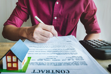 Business Home loan, Real Estate. Young man calculate loans with calculator and holding pen to...