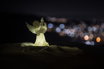 christmas angel on blur bokeh city lights at night on background. Little white guardian angel in snow.