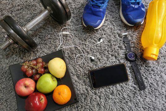 Healthy and fit lifestyle concept. Water bottle, sport shoes, fruits and dumbbell image