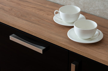 Two empty coffee cups with a saucer on the console