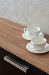 Two empty coffee cups with a saucer on the console