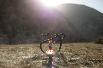 Hookah, traditional arabic waterpipe, direct sunset light, outdoor photo. Mountain background or Silhouettes of hookah on sunset background. Outdoor. Selective focus