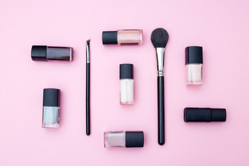 Nail polish and brush on a pink background. Flat lay