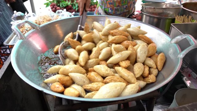 Fish ball made from clown knifefish was fried by female street vendor beside the street, Thailand food street style.