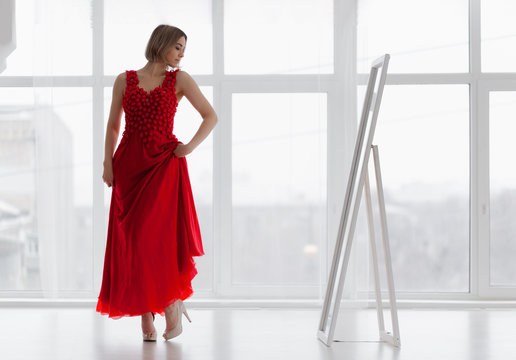 Woman in red dress looks in the mirror