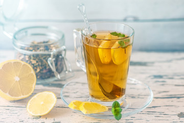 Cup of Lemon tea with lemon slices and mint on light wooden table