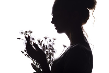 silhouette portrait of a girl with a bouquet of dry flowers, face profile of a dreamy young woman on a white isolated background