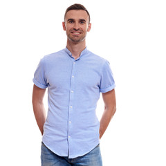 Fototapeta premium Casually handsome. Confident young handsome man in jeans shirt keeping arms crossed and smiling while standing against white background