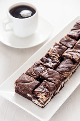 Chocolate brownie with a cup of coffee. High key.