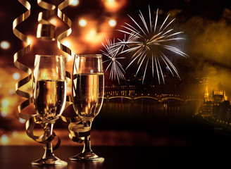 two champagne glasses with ribbons against holiday lights and fireworks - New Year celebrations