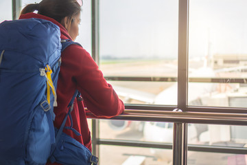 Fototapeta na wymiar Traveler asia woman standing at the window in hall airplane departure with backpack , Selective focus, Travel concept.
