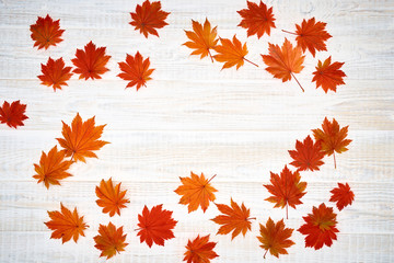 Naklejka na ściany i meble Faded autumn leaves on white wooden background.