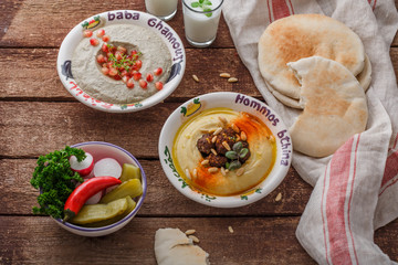 Hummus in traditional lebanon plate on a rustic table with vegetables