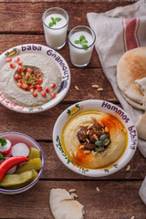 Hummus and baba ganoush with fresh vegetables in traditional plates