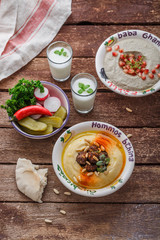 Hummus in traditional lebanon plate on a rustic table with vegetables