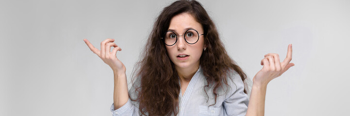 Obraz premium Young brunette girl with glasses. The girl spread her hands to the sides.