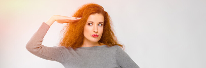 Portrait of beautiful redhead happy smiling young woman in gray clothes showing funny gesture on gray background