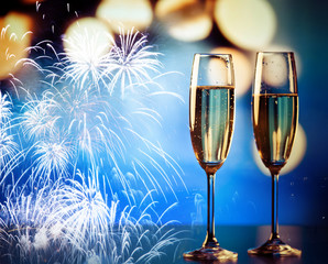 two champagne glasses against holiday lights and fireworks - new year celebration