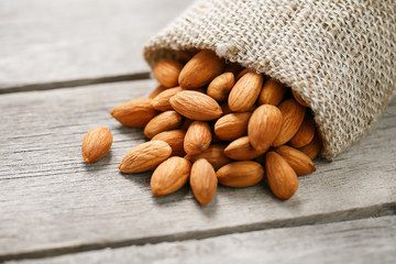 Almond nuts in a burlap bag on a wooden gray background.