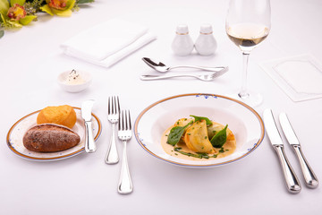 Giving of a dish at restaurant, dumplings in sauce with greens, moves with a plate of white and black loaf with white wine