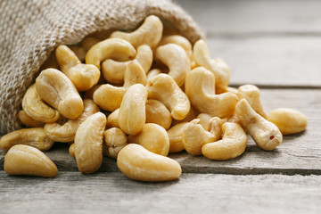 Cashew nuts in burlap bag on wooden gray background . Healthy food