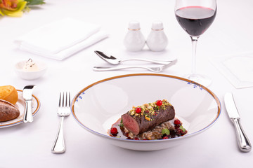 A meat stake on a pillow from porridge with berry sauce