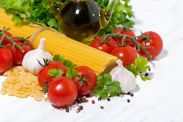 spaghetti, fresh tomatoes and spices on a white table, closeup