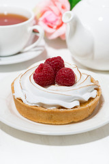 sweet tartlet with meringue and raspberry on white table, vertical