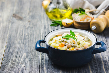 Sauerkraut soup with beans, vegetables and meat in a pot on wooden background. Selective focus, space for text.