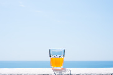 A glass filled with juice against the backdrop of the sea.
