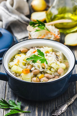 Sauerkraut soup with beans, vegetables and meat in a pot on wooden background. Selective focus, space for text.