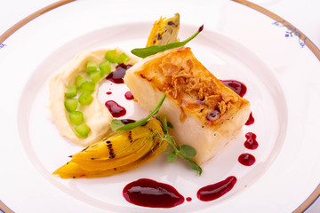 A halibut on a grill with caramelized onions and berry sauce