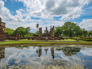 Fototapeta na wymiar Ancient Statue reflection in the water in Wat mahathat Temple Area At sukhothai historical park,Sukhothai city Thailand