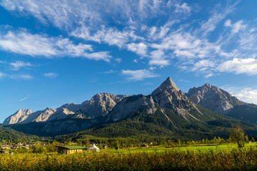 Panoramic view of high mountains in Austria with a green meadow in the foreground
