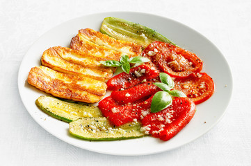 fried cheese with roasted zucchini, bell pepper, and tomato flavoured with olive oil, vinegar, and garlic sprinkled with black pepper decorated with basil 