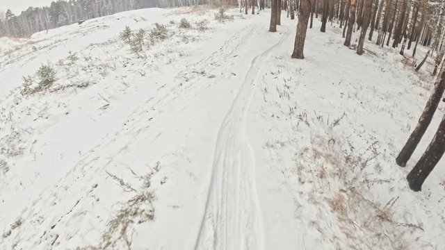 Pov view. Handheld gimbal stabilization. Professional extreme sportsman biker riding a fat bike in outdoors. Cyclist ride in the winter snow forest. Man does trick on a mountain bicycle with big tire.